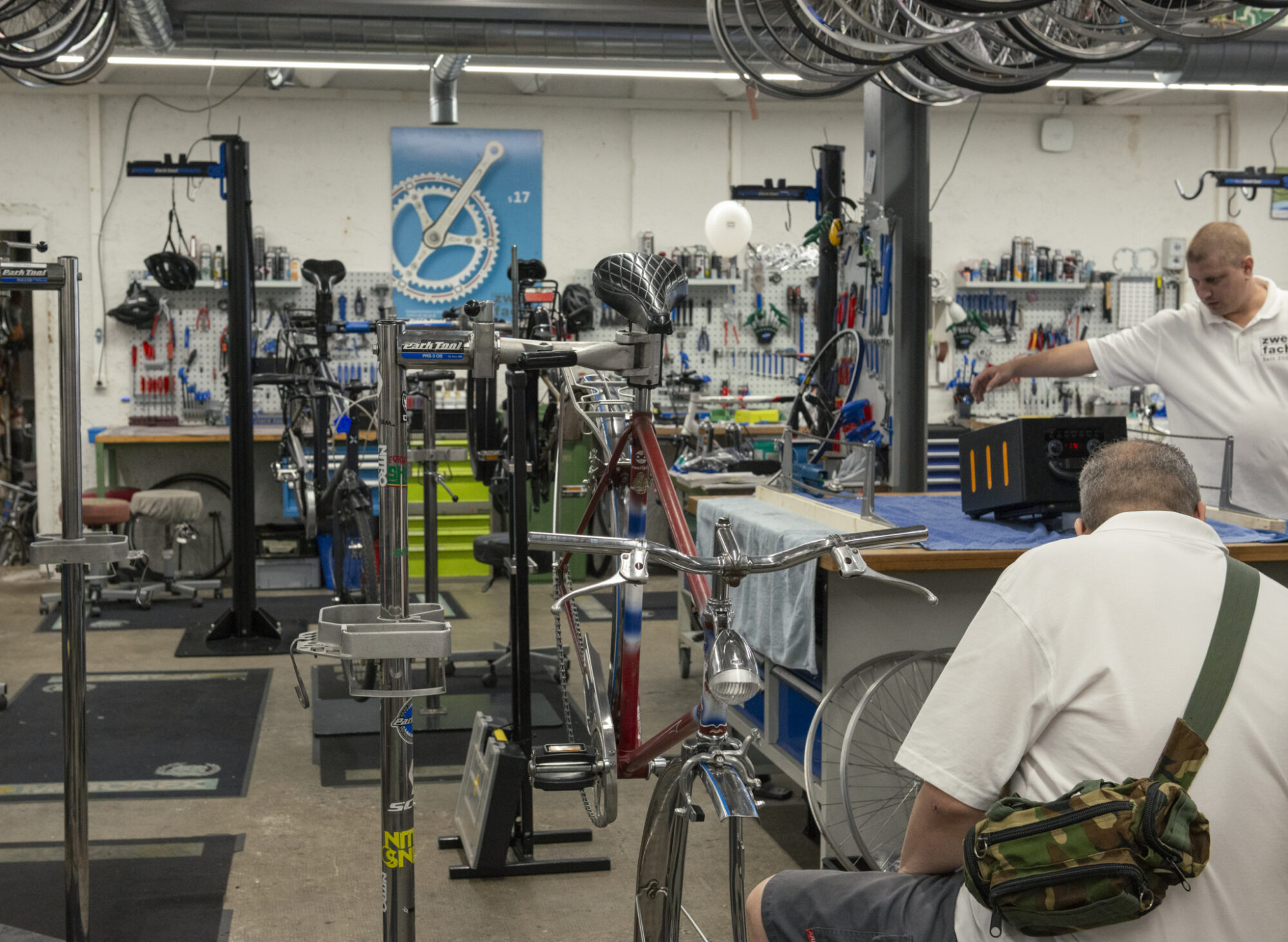 Zwei Männer arbeiten in einer gut ausgestatteten Fahrradwerkstatt an verschiedenen Velos.