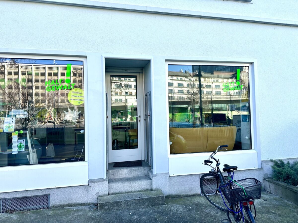"Ein Fahrrad steht vor einem Gebäude mit einem 'Halt der Gewalt'-Schild im Fenster."
