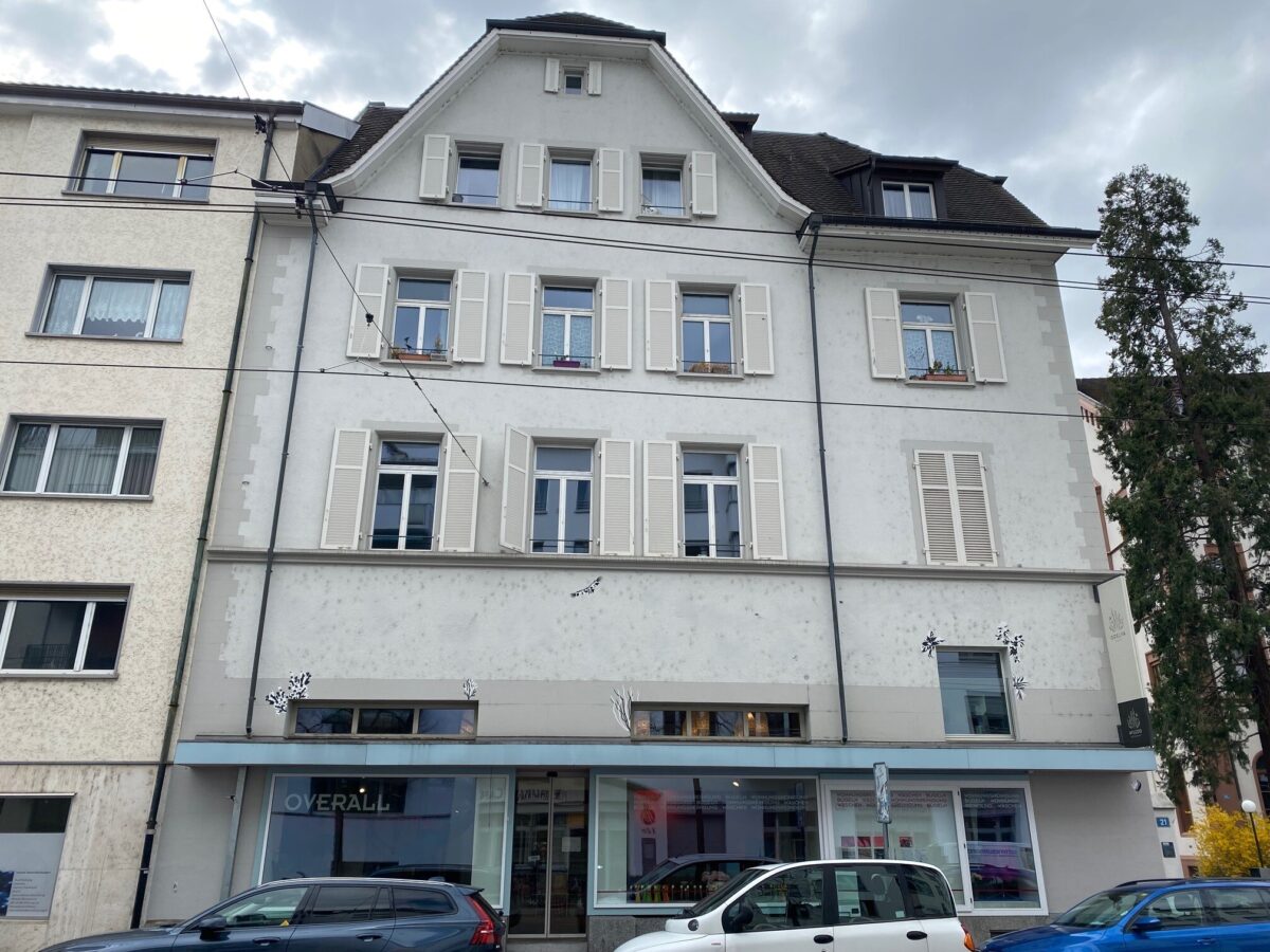 Ein mehrstöckiges Gebäude mit weißen Fenstern und einem Geschäft im Erdgeschoss.