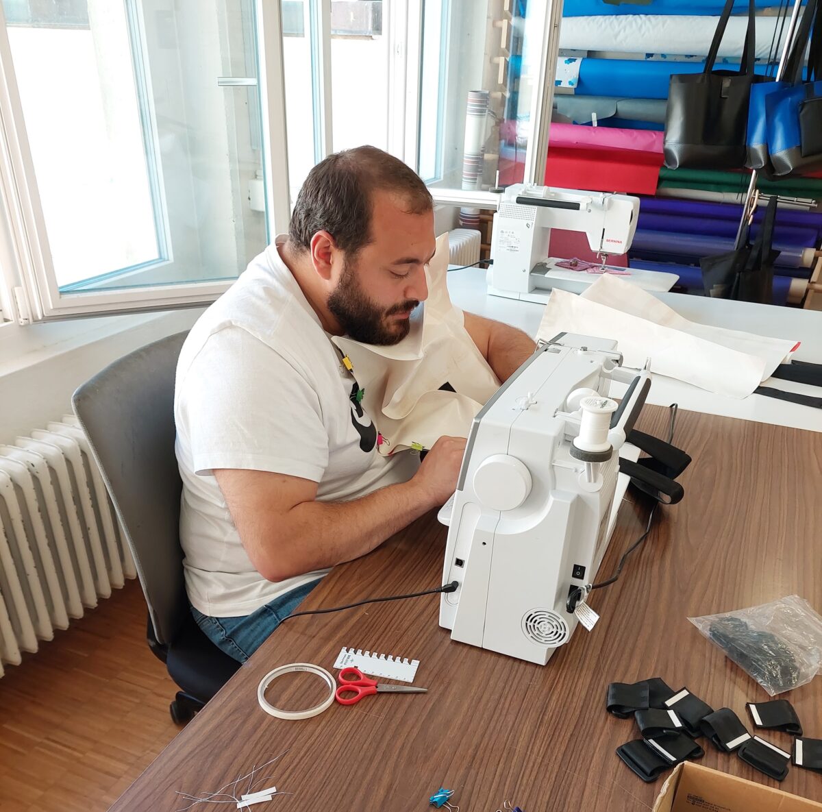 20230614 111929 1 Ein Mann arbeitet konzentriert an einer Nähmaschine an einem Tisch mit Nähutensilien.