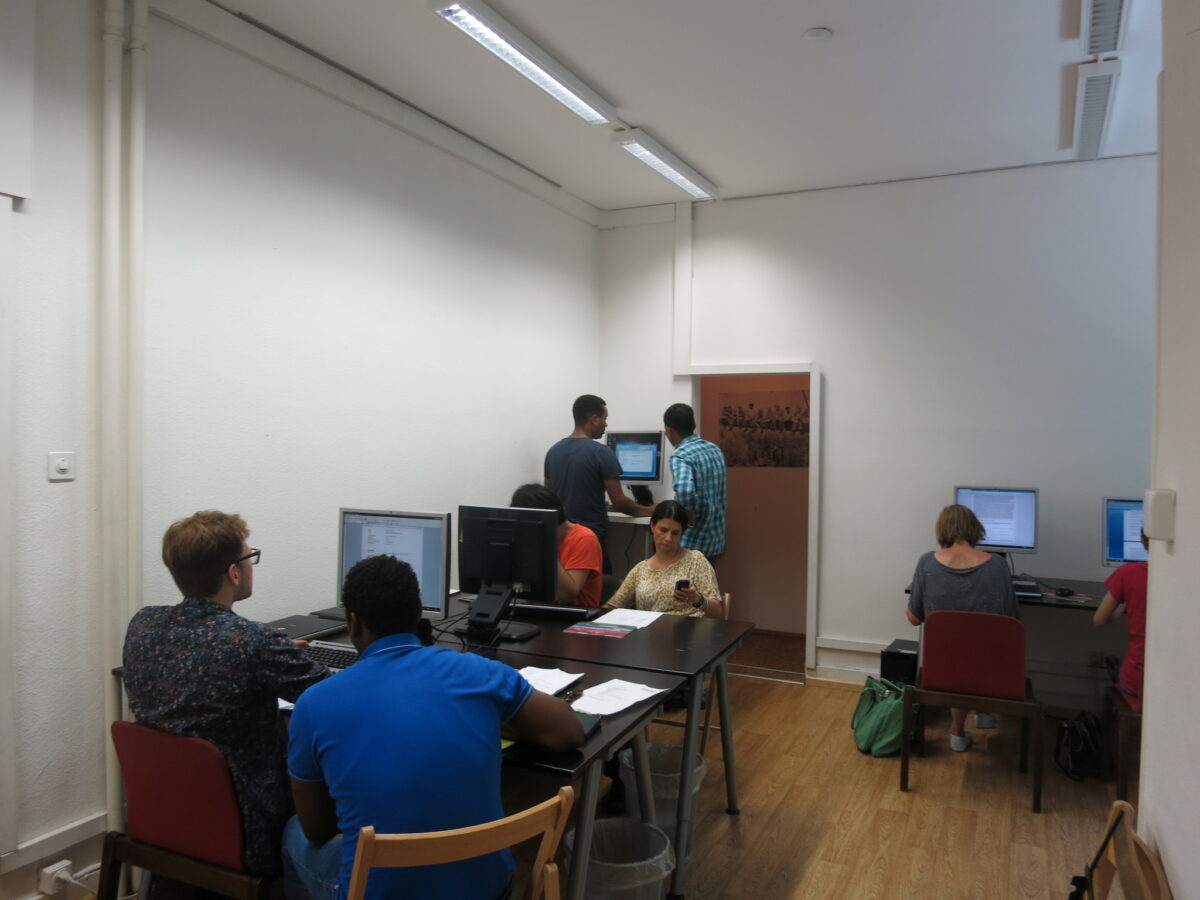 Menschen arbeiten konzentriert an Computern in einem hellen Raum.