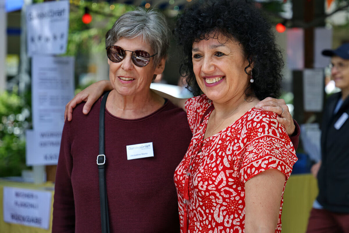 Jacqueline and ana 1 Zwei Frauen lächeln und umarmen sich bei einer Veranstaltung.