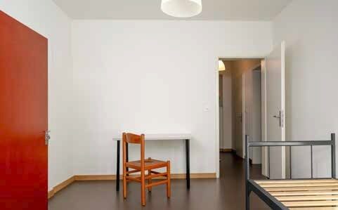 Ein einfaches Zimmer mit einem Tisch, einem Stuhl und einem Bett.